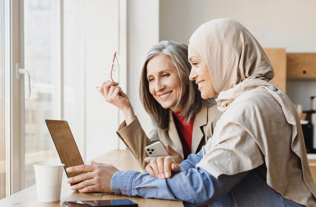 Two individuals looking at a laptop and smiling. 