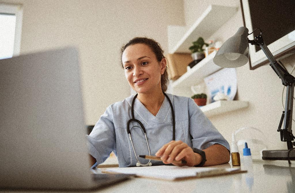 doctor smiling and looking at laptop in office