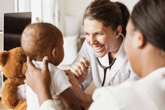 A young doctor examining a baby.