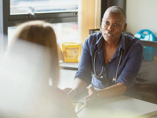 A doctor speaking to a patient in their office.