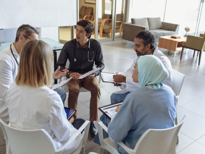 Five doctors sitting in a circle and talking.