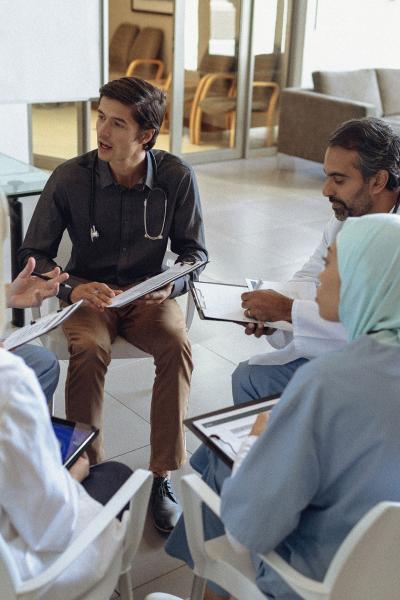 Five doctors sitting in a circle and talking. 