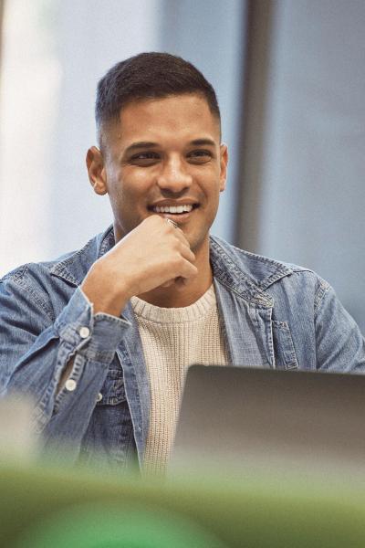 An inidividual sitting in a group setting with a laptop. 